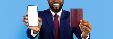 Man in Suit Holding Smartphone and Passport Against Blue Background With a Big Smileの写真素材