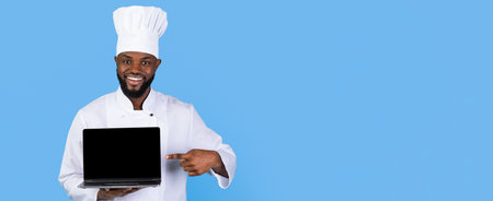 Chef Points at Laptop Showing Culinary Expertise in a Bright, Colorful Kitchen Settingの写真素材