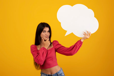 Idea concept. Armenian woman holding empty speech bubble over her head and thinking, yellow...