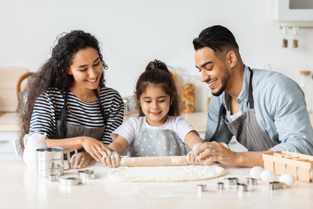Smiling middle-eastern family parents and kid making biscuits at home