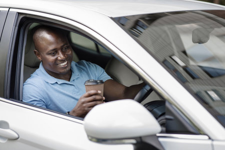 Relaxed black driver enjoying coffee break inside carの写真素材