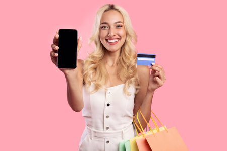 Smiling woman showing blank smartphone screen and credit card