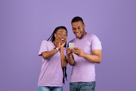 Portrait of surprised black couple using smartphoneの写真素材