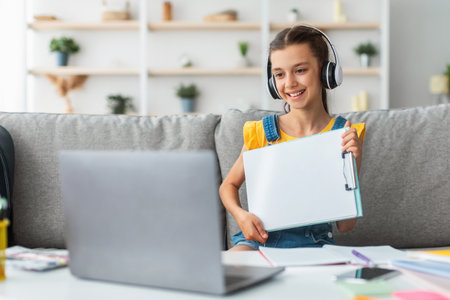 Girl sitting at desk, using pc, showing paper