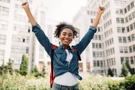 Black Student Girl Shaking Fists Celebrating Success In College Outdoorの写真素材