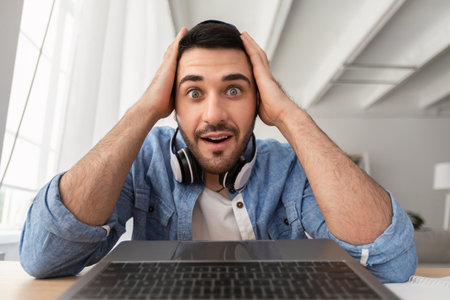Surprised man having video call using laptopの写真素材