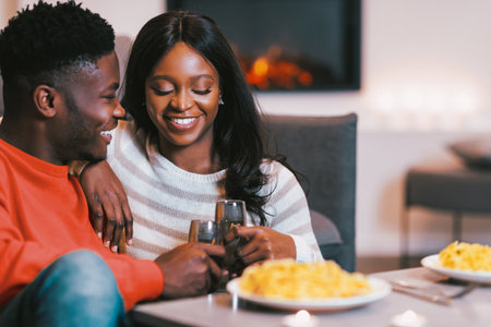 Couple Enjoys Dinner Together in Cozy Setting With Warm Lighting and Food on the Tableの写真素材