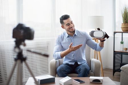 Tech product review. Male vlogger presenting VR headset, recording video about innovative device for...