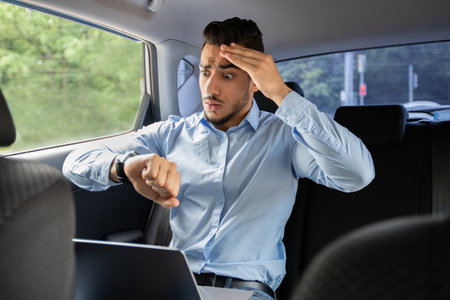 Worried arab businessman looking at watch while sitting in car