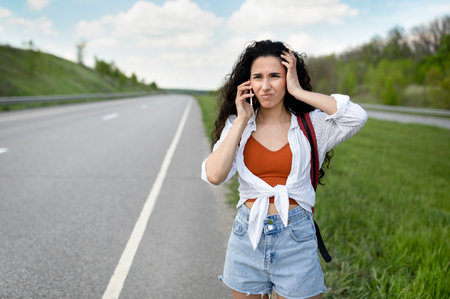 Confused young woman standing along road, feeling lost, calling on smartphone, checking travel options outdoorsの写真素材