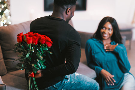Man Surprises Woman With Red Roses During Indoor Celebration in Modern Living Spaceの写真素材