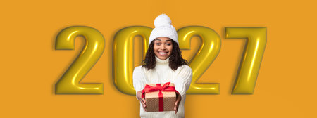 Celebrating the New Year With a Woman Holding a Gift in Front of Golden Numbersの写真素材