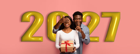 Couple Celebrates New Year With Gift and Festive Mood in Front of Large Golden Numbersの写真素材