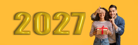 Couple Celebrating New Year in 2027 With a Gift and Playful Surpriseの写真素材