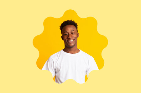 Smiling Young Man Poses in a Bright Setting Surrounded by Yellow Backgroundの写真素材