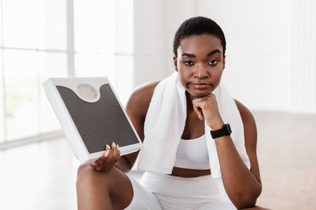 Portrait of Unhappy African Woman Holding Bathroom Scales. Slimming