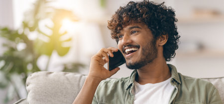 Man Talking on Phone While Sitting on Couch in Living Room During Daylight Hours