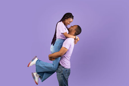 African American man lifting his girlfriend up at studioの写真素材