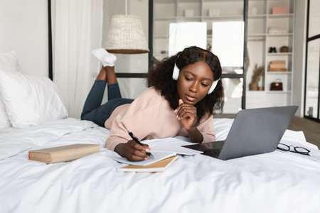 African american millennial woman using laptop taking notes at homeの写真素材