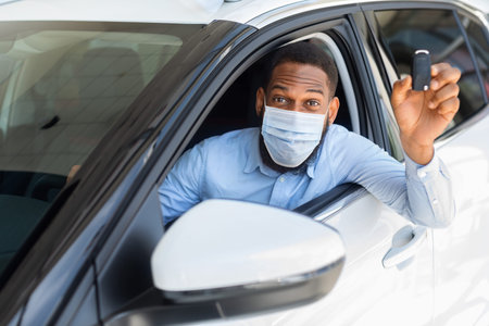 Happy African Man In Mask Sitting In Car And Showing Key