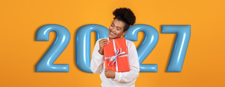 Collage of a Woman Holding a Gift in Front of a Colorful 2027 Backdropの写真素材