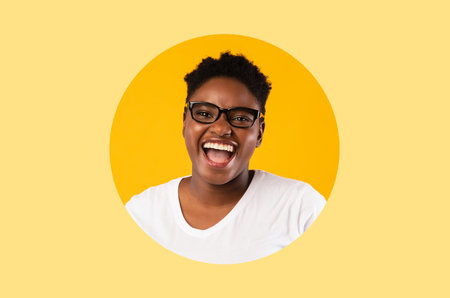 Smiling Person With Glasses Shares Joy Against Bright Yellow Backdrop in a Cheerful Settingの写真素材