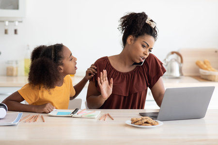 Teen girl sitting by working mom, kitchen interior