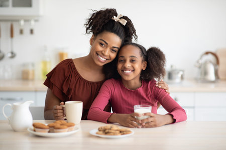 Loving black mother and daughter enjoying fresh cookiesの写真素材