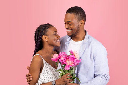 Happy black man making surprise for woman giving flowersの写真素材