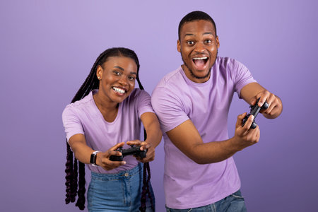 Excited African American couple playing video games together with joysticks