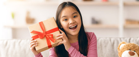 Child Opens Gift With Joy in Living Room During Celebration With Family and Friendsの写真素材
