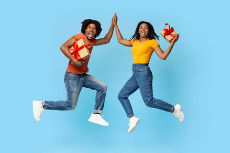 Positive black man and woman with presents giving high five