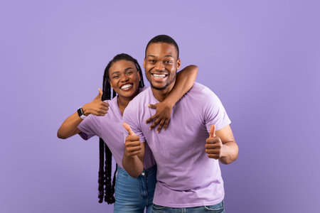 Happy black couple gesturing thumbs up and smiling