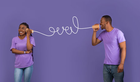 African American couple talking through tin can telephone. Love Messageの写真素材