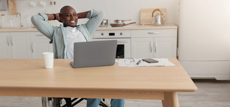Man With Dark Skin Working on a Laptop at Home in Modern Kitchen With Relaxed Posture