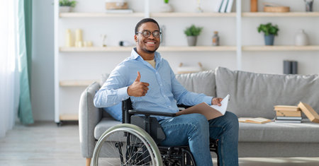 Man Using a Wheelchair Gives Thumbs up While Sitting in a Bright Living Room With Modern Decorの写真素材