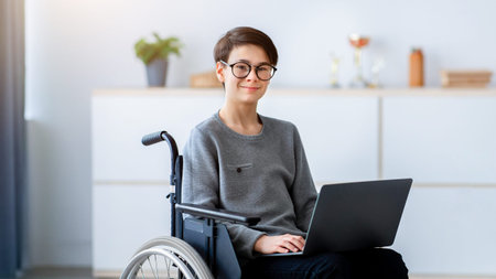 Young Boy Using a Wheelchair While Working on a Laptop at Homeの写真素材