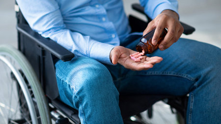 Man Using a Wheelchair Takes Medication With Care in a Bright Space During the Dayの写真素材