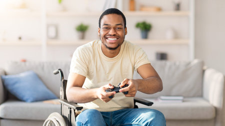 Young Man With Dark Skin Enjoys Gaming in a Modern Living Room While Using a Wheelchairの写真素材