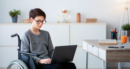Young Boy Using a Wheelchair Working on a Laptop in a Modern Workspace