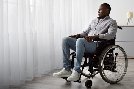 Man Using a Wheelchair Looking out a Window in a Bright, Modern Room