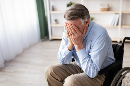 Man Using a Wheelchair Shows Signs of Distress in a Bright Indoor Space During the Dayの写真素材