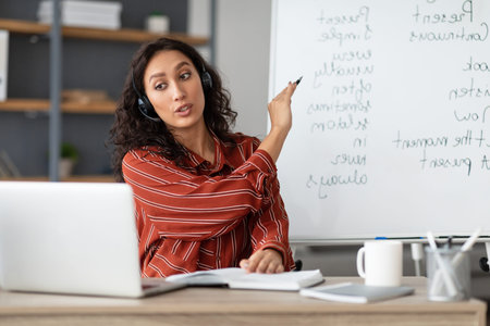 English teacher pointing on board, videochatting with sudents online