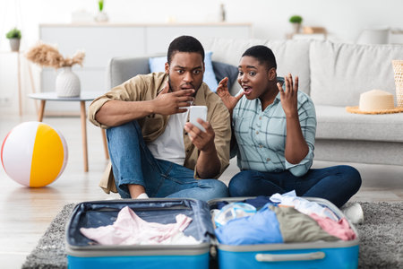 Shocked Black Tourists Couple Using Cellphone Reading Shocking News Indoorの写真素材