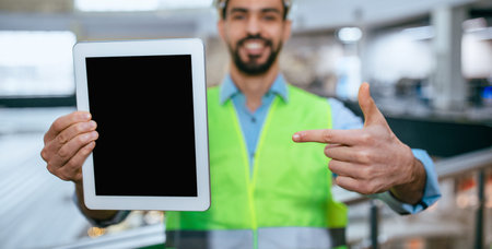 Construction Worker Shows Tablet While Pointing in a Warehouseの写真素材
