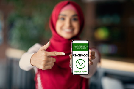 Middle-eastern lady in hijab showing international certificate on smartphoneの写真素材