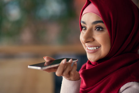 Closeup of pretty muslim woman recording audio message on cellphone