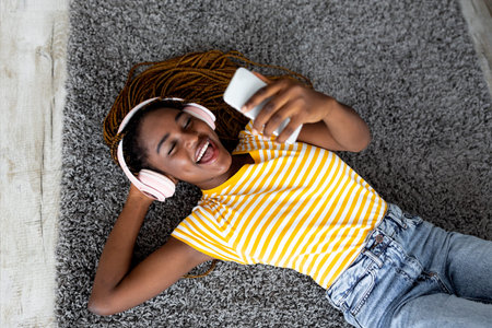 Joyful afro-american woman in headset taking selfie on smartphone