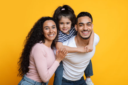 Portrait Of Happy Parents With Little Daughter Over Yellow Background