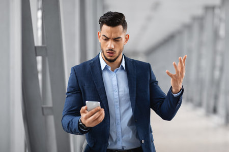 Portrait Of Worried Businessman Reading Message On Smartphone In Airportの写真素材